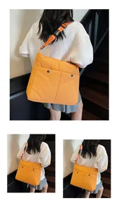 Detail of orange messenger bag featuring dual front pockets and adjustable buckle strap