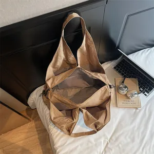Large khaki canvas tote bag with striped lining shown in a minimalist home office setting