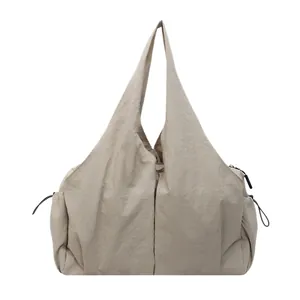 Minimalist beige nylon tote bag with drawstring detail and large capacity on white background