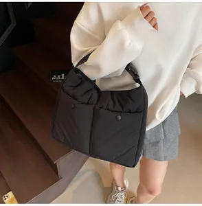 Detail of black quilted shoulder bag featuring dual front pockets with snap buttons