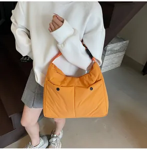 Detail of bright orange quilted shoulder bag with dual pockets and black buckle strap