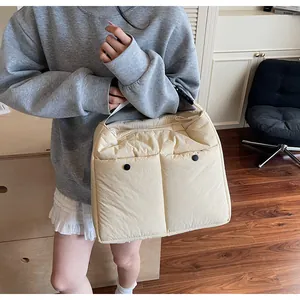 Detail of large quilted cream shoulder bag showing twin front pockets with black buttons
