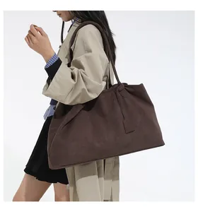 Detail of dark brown suede tote bag with minimalist cut and long shoulder strap