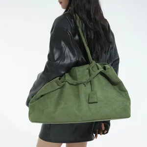 Large green suede tote bag shown on a model wearing a black leather jacket