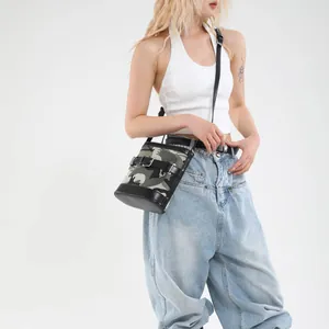 Fashionable camouflage bucket bag with leather trim worn by model in streetwear style