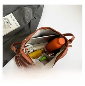 Ruime binnenkant van bruine lederen shopper met laptop en dagelijkse benodigdheden