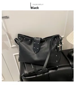 Detail van zwarte lederen tote bag met zilveren metalen studs en kruishanger versiering