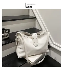 Detail van de witte leren shopper met zilveren klinknagels en kruishanger