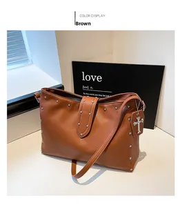 Detail van de bruine leren tote bag met zilveren klinknagels en kruishanger