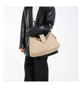 Detail van een beige shopper met lychee-textuur en zilveren studs op een model