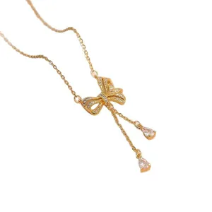 Elegante goldfarbene Schleifenkette mit funkelnden Kristallen und hängenden Quasten