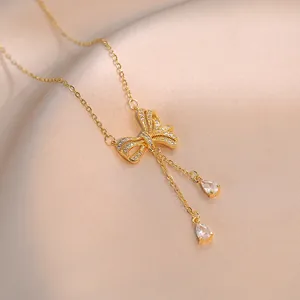 Elegante goldene Schleifenhalskette mit Kristallen und Zirkonia-Quasten auf Seidenhintergrund