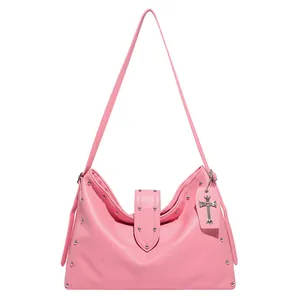 Roze draagtas met litchi-textuur, zilveren studs en kruishanger op witte achtergrond