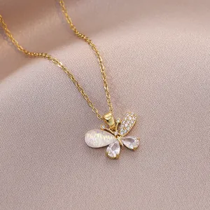 Collier papillon doré élégant avec opale et zircons sur fond en soie de couleur champagne