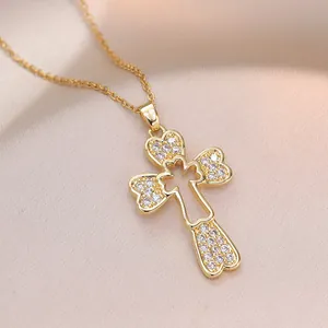 Collana con croce dorata con punte a cuore e zirconi su sfondo di seta color champagne