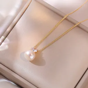 Détail d'un pendentif en perle d'eau douce dorée avec zircon sur une chaîne fine
