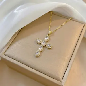Close-up of golden cross pendant necklace with zircon stones on a satin background