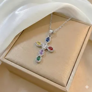 Detailed shot of silver cross pendant with colorful zircon stones on elegant white satin