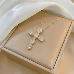 Detailed view of a gold cross pendant necklace with marquise-cut crystals on silk fabric