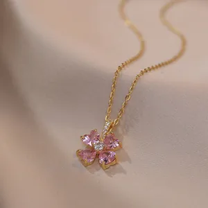 Elegante collar dorado con colgante de flor de corazones rosas sobre fondo de seda