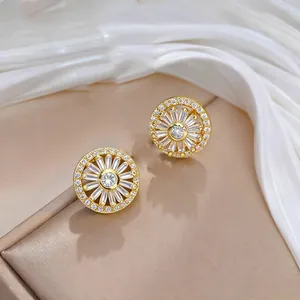 Dettaglio di orecchini a lobo a girasole dorati con zirconi su espositore beige
