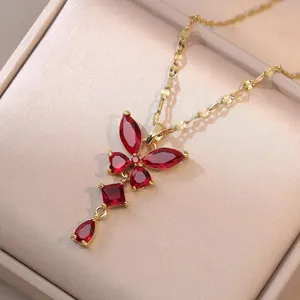 Gros plan détaillé d'un collier doré avec un pendentif papillon rouge en pierres précieuses
