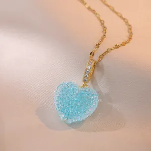 Elegant gold heart pendant necklace featuring blue crystals on champagne satin background