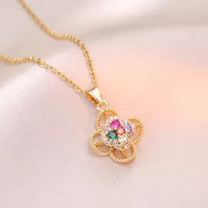 Collier doré avec pendentif trèfle orné de zircons colorés sur fond de satin rose