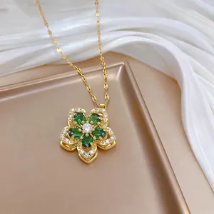 Detail of a rotating flower necklace with green stones on a luxury gold tray