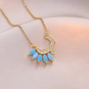 Collier bohème doré avec pendentif lune et pierres turquoise sur fond en tissu