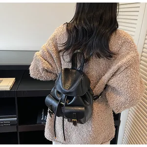 Dettaglio di un mini zaino in pelle nera con doppie tasche anteriori su una modella
