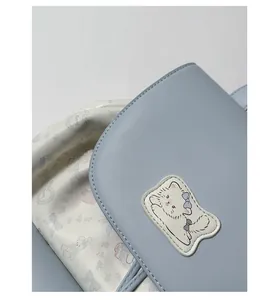 Detailed close-up of light blue leather bag with white cat patch and bunny floral lining
