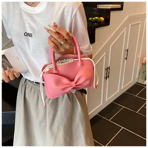 Pink bucket bag with a large bow, silver heart pendant and white drawstring closure details