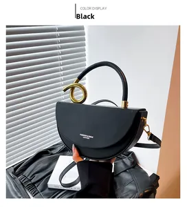 Detail of black semi-circular saddle bag with gold metal buckle and leather strap