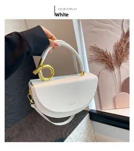 Detail of white semi-circular leather handbag with gold ring handle and adjustable strap