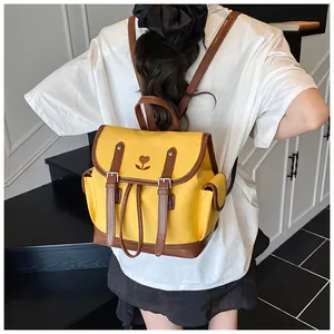Vue arrière d'un sac à dos vintage jaune avec bretelles brunes et broderie cœur
