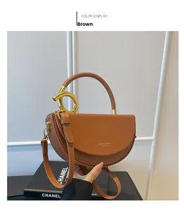 Detail of a brown crescent-shaped handbag featuring a gold ring buckle and smooth texture