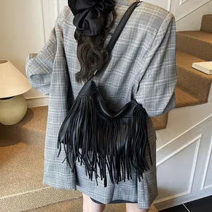 Retro black leather fringe hobo bag with tassel detail shown on a model in a blazer