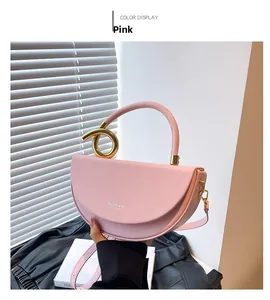 Detail of pink half-moon handbag with gold circular metal handle and thin shoulder strap