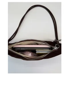 Vue détaillée de l'intérieur d'un sac croissant en daim marron avec objets du quotidien