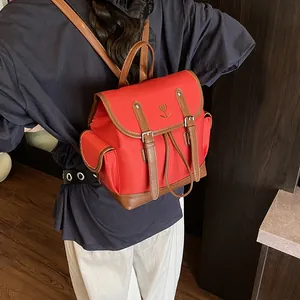 Sac à dos vintage rouge avec bordure en cuir marron et broderie cœur porté par un modèle