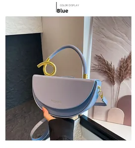 Detail view of a light blue crescent handbag with gold knot handle and thin shoulder strap