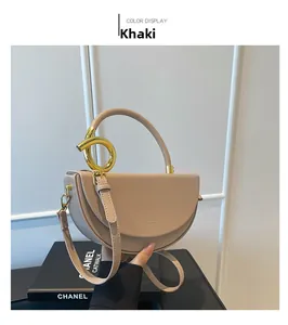 Detail of khaki saddle bag featuring golden ring handle and smooth leather texture