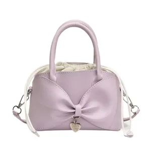 Light purple bucket bag with large bow and heart charm on a clean white background
