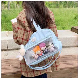 Dettaglio della borsa ita azzurra con finestra trasparente che mostra bambole di peluche