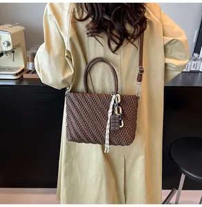 Dettaglio della borsa a mano marrone scuro con trama intrecciata e ciondolo cioccolato