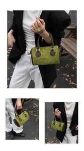 Details einer grünen Wildleder-Zylindertasche mit braunen Ledergriffen und goldenen Metallringen
