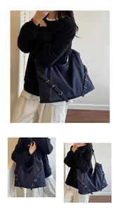 Detail of dark blue denim tote bag featuring white contrast stitching and metal buckles