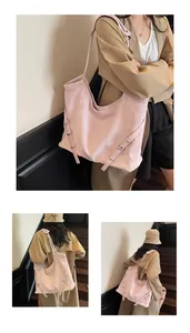 Detail of light pink large tote bag with side metal buckles on soft leather texture
