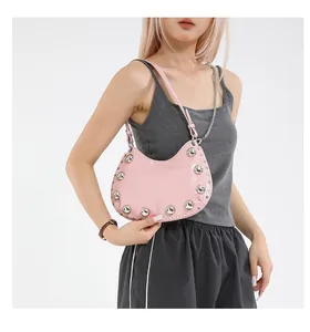 Detail of pink dumpling bag with large silver rivets and metallic chain strap shown on model